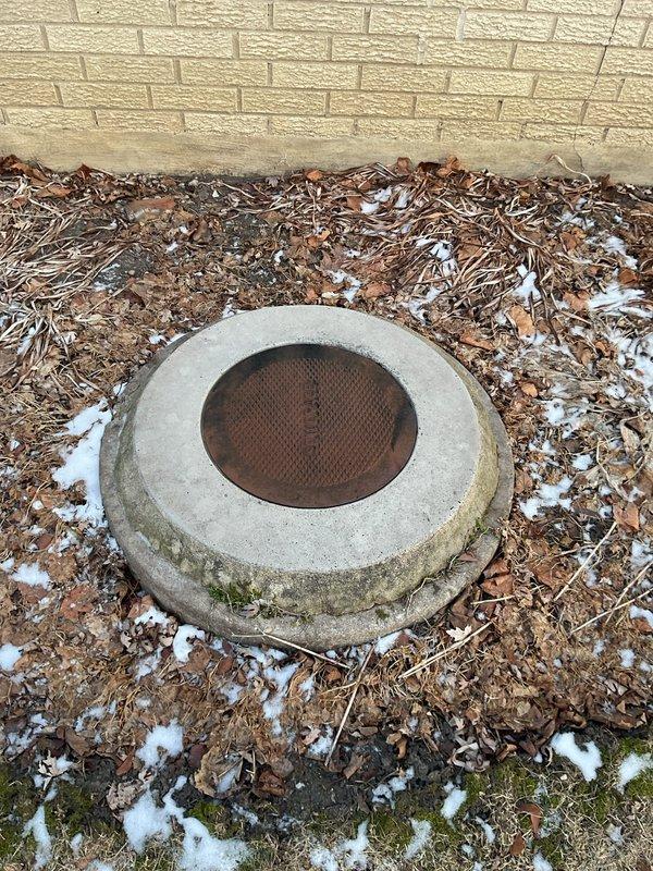 Successfully cleared main line blockage by rodding, and removed accumulated grease from catch basin. Visual inspection revealed significant pipe corrosion and rust buildup in the drainage system, with debris accumulation around the exterior drain cover.