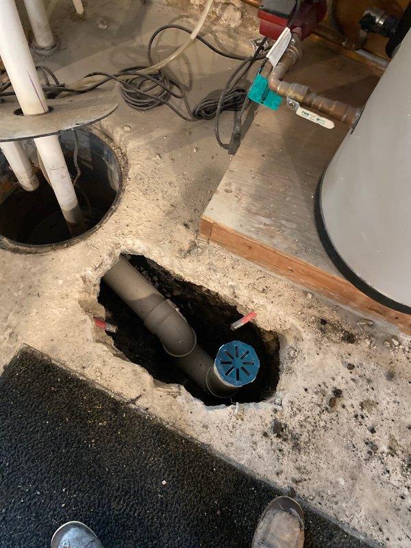 Collected down payment for repair job sold by Jon H. Cut access hole in basement concrete floor to expose damaged drain pipe. Documented existing plumbing infrastructure and significant cracking in concrete drain cap/floor with evidence of water infiltration requiring repair.