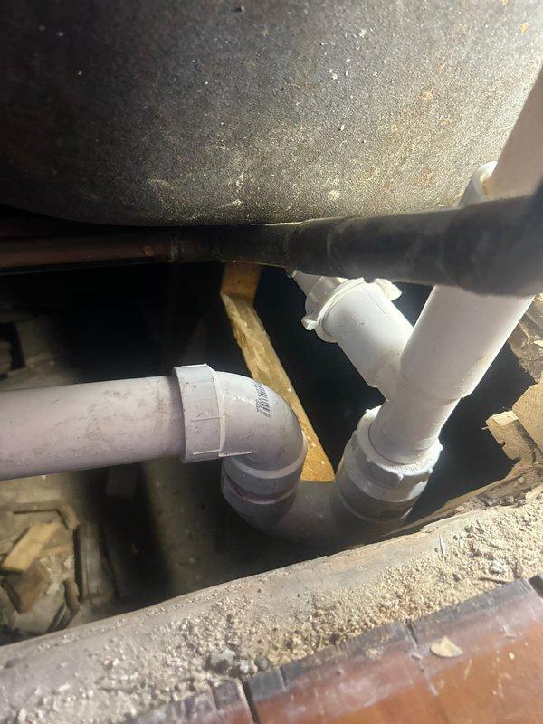 Responded to service call for slow-draining kitchen sink and bathtub. Inspected PVC drainage system in crawlspace, finding significant buildup causing restricted flow. Accessed additional plumbing components through wall opening to locate and clear blockage. Successfully restored normal drainage function to both fixtures.