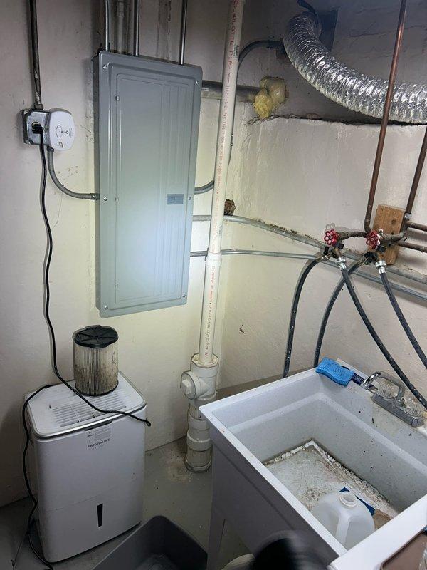 Responded to emergency basement flooding caused by drain backup. Installed portable dehumidifier with air filtration system to begin moisture extraction process. Inspected plumbing system including PVC drainage pipes, copper supply lines, and associated valves. External inspection revealed potential seasonal factors contributing to backup with partial snow melt and ground saturation around foundation.
