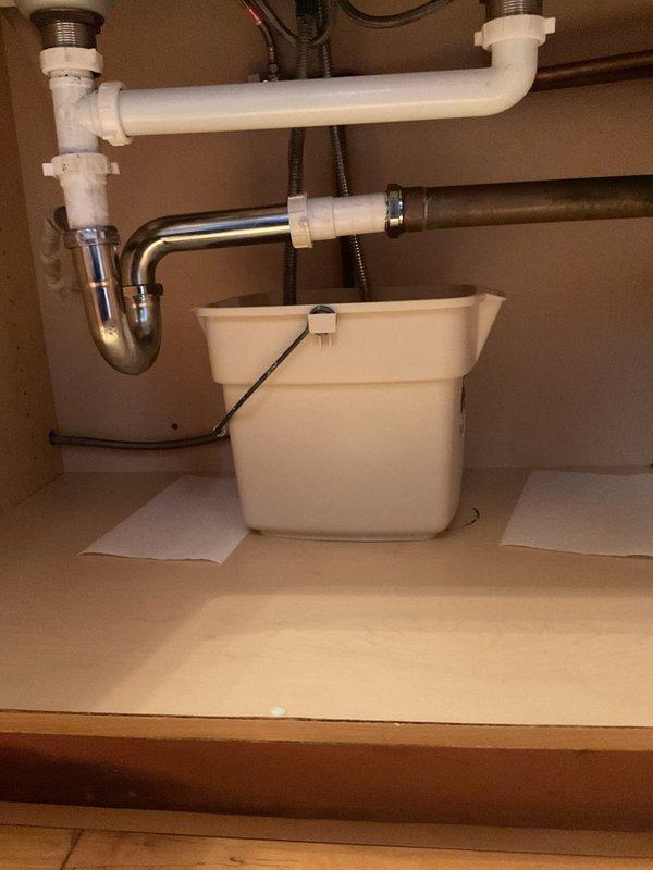 Responded to leak report at kitchen sink. Visual inspection revealed water leakage from P-trap assembly connecting to PVC drain pipes. Installed temporary catch container beneath affected area to prevent water damage while repairs were conducted. Completed replacement of deteriorated P-trap connection, ensuring proper seal and alignment with existing drain system.
