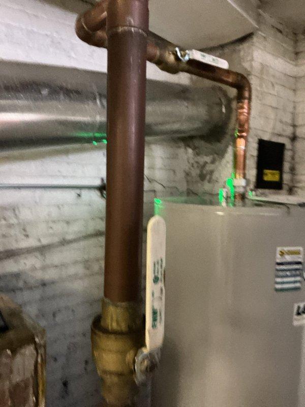 Completed installation of copper pipe with 90-degree elbow joint connecting to water heater system. Installed brass valve fitting on vertical copper line and ensured proper connection to horizontal supply line. All connections tested and verified leak-free with system functioning as designed.