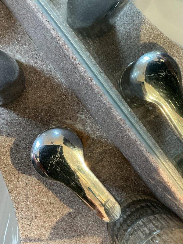 Performed follow-up inspection on bathroom fixtures. Documented chrome faucet handles installed on stone countertop and white porcelain sink with metal drain. Project on hold pending tile removal by separate contractor.