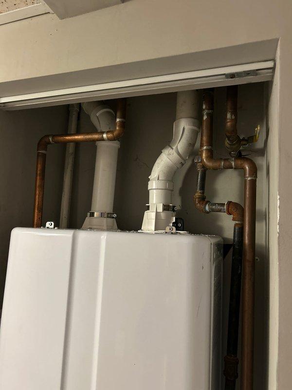Successfully installed a Navien wall-mounted water heater in utility area. Installation included complete copper and PVC piping connections, valve installations, and a sediment filter mounting. System was properly configured with temperature settings and all connections were verified for proper operation.