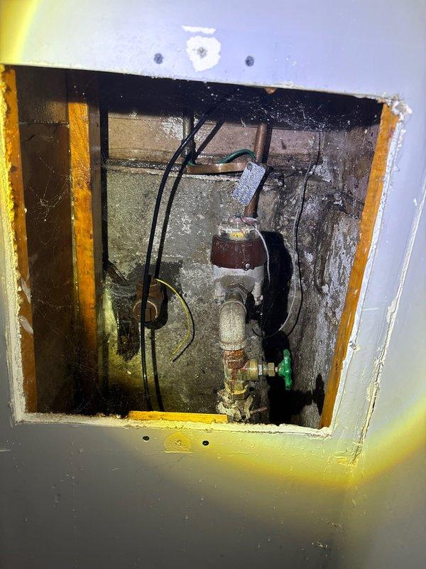 Responded to emergency call for burst pipe. Upon inspection, discovered heavily corroded elbow joint with active water leakage in wall access panel. Replaced deteriorated pipe fitting to resolve the leak and prevent further water damage.
