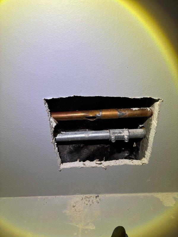 Responded to emergency call for a burst pipe in customer's basement. Upon inspection, discovered a frozen copper pipe that had ruptured, causing water damage to surrounding wooden joists. Cut access hole in wall to reach affected area, replaced damaged section with new copper pipe and PVC fitting, and restored water service to the home.