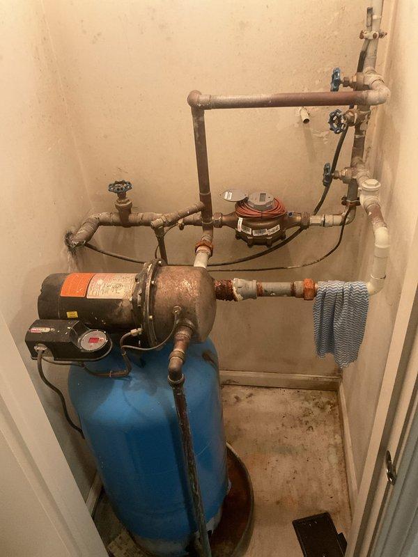 Conducted comprehensive inspection of aging booster pump system showing significant rust deterioration at the base and connection points. Examined the blue cylindrical pressure tank, associated copper/PVC piping network, and control valves for overall condition assessment. Provided customer with replacement options for the deteriorating pump assembly.