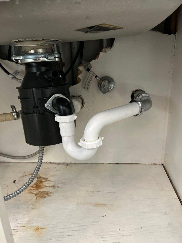 Responded to priority service call regarding leaking garbage disposal unit. Upon inspection, found significant water damage and rust on cabinet floor with deterioration to cabinet ceiling. Replaced faulty disposal unit, ensuring proper connection to existing PVC P-trap assembly and electrical conduit. Verified proper operation and confirmed no leaks after installation.