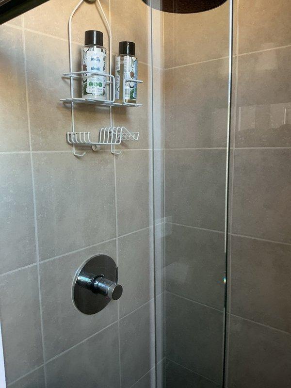 Assessed existing bathroom for plumbing modifications to accommodate new vanity installation, requiring sink plumbing relocation. Additionally, evaluated shower system for valve and fixture replacement. Current shower features standard chrome control knob with wall-mounted installation in tiled enclosure.