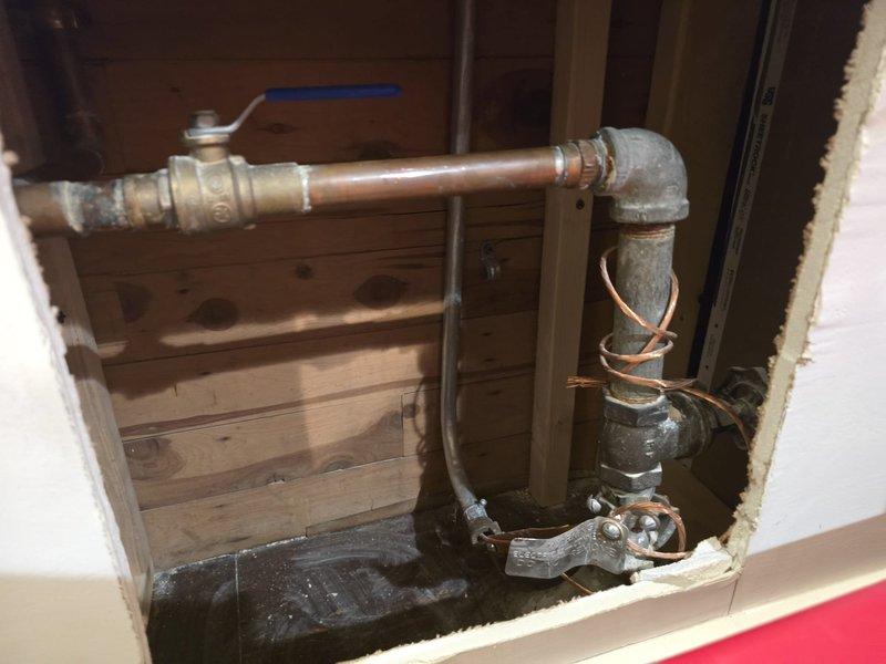 Responded to emergency call for frozen pipes in the morning. Located affected plumbing in wall cavity, which showed signs of previous water damage. Inspected exterior ground conditions, confirming frost penetration as likely cause. Thawed copper and galvanized steel pipe assembly, verified proper operation of shutoff valve, and confirmed water flow restoration.