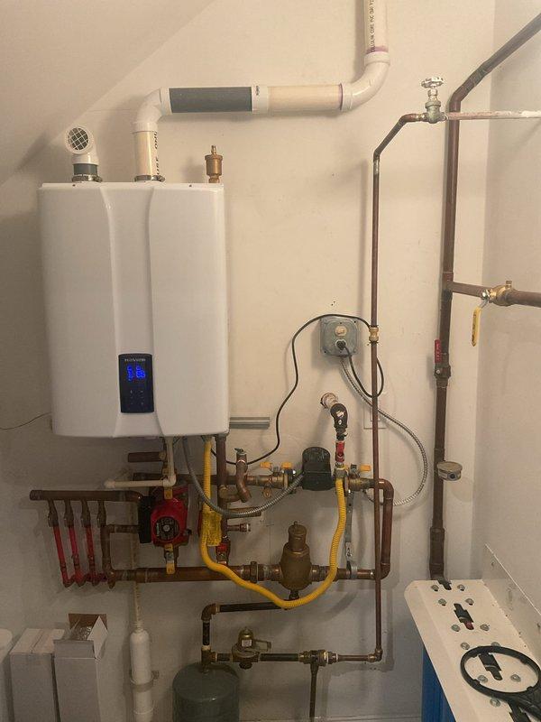 Performed maintenance service on Rheem tankless water heater system that supplies radiant floor heating. Addressed loose exterior venting pipes that were leaking, resealing and securing all PVC vent connections. Inspected circulation pump, expansion tank, and associated brass valves/fittings. Verified proper operation of the tankless unit itself, which was functioning correctly. All components now properly sealed and operational.