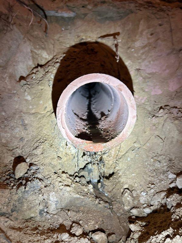 Excavated area to access damaged clay sewer pipe showing signs of deterioration with visible black residue and water damage. Job was sold by Jon Hartman and scheduled for Monday with Mikey's approval, no down payment required.