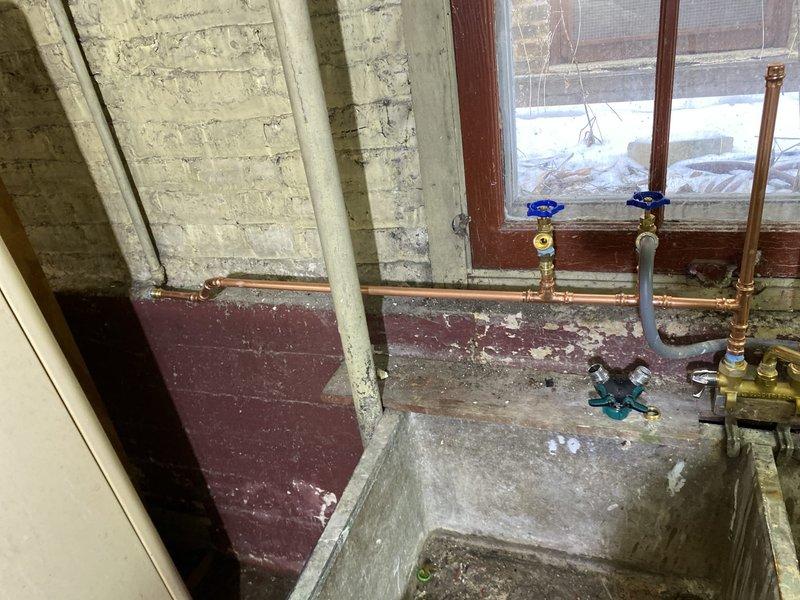 Completed copper plumbing work on utility sink system in basement. Installed new shutoff valves with blue handles and replaced deteriorated copper pipe sections. Ensured proper connection to concrete dual-basin utility sink and tested for leaks.