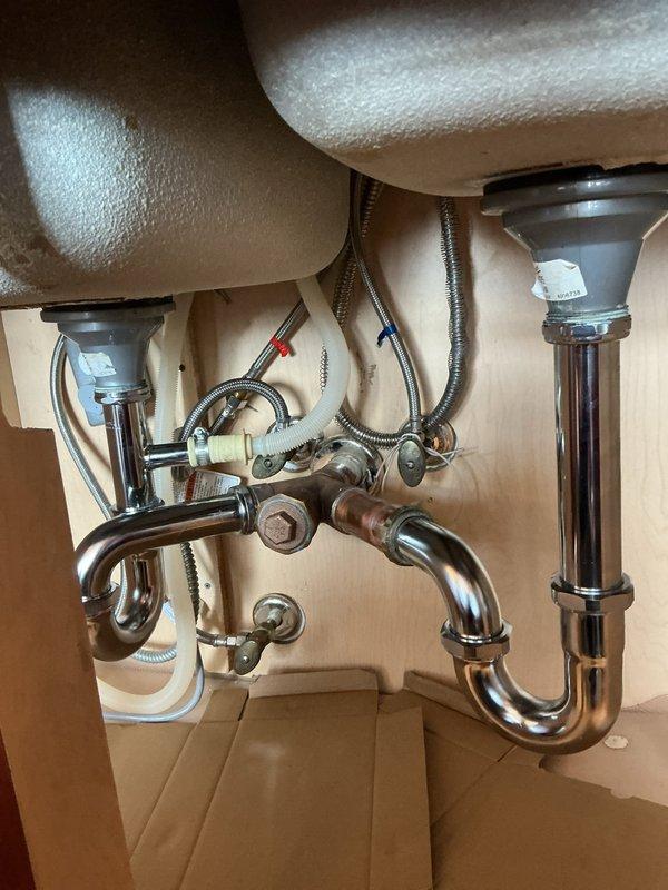 Successfully completed installation of chrome p-trap assembly for dual-basin sink in wooden vanity cabinet. The job included connecting the drain assemblies to both sink basins, securing all fittings and connection points, and ensuring proper alignment of all plumbing components. Final inspection confirmed no leaks and proper drainage function.