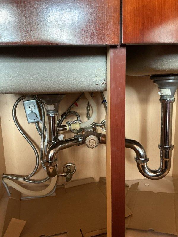 Successfully completed installation of chrome p-trap assembly for dual-basin sink in wooden vanity cabinet. The job included connecting the drain assemblies to both sink basins, securing all fittings and connection points, and ensuring proper alignment of all plumbing components. Final inspection confirmed no leaks and proper drainage function.