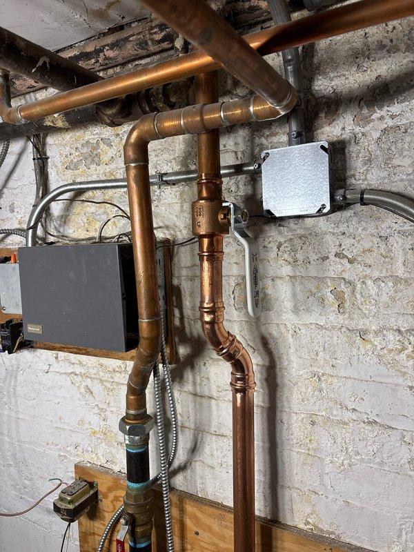 Successfully collected down payment for plumbing repair job sold by Nick B. Documentation includes photos of the existing copper pipe infrastructure in the utility area and the dual red circulation pumps with green flanges mounted on plywood, which will be addressed during the scheduled repair work.