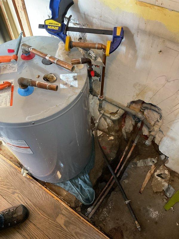 Responded to emergency call for water backing up through floor. Upon inspection, discovered significant water leak in utility room with previous technician having removed water heater. Diagnosed issue as deteriorated copper supply lines with visible corrosion causing water intrusion into wall and floor. Replaced damaged plumbing connections, restored water service, and verified system functionality with no further leakage.