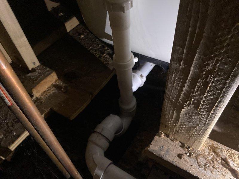 Conducted leak investigation for reported shower drainage issue affecting bedroom and wall below. Accessed utility space to inspect PVC drainage system. Found damaged elbow joint in shower drain line with visible deterioration of surrounding wooden structural supports. Identified this as the source of water intrusion causing damage to the bedroom ceiling and wall.