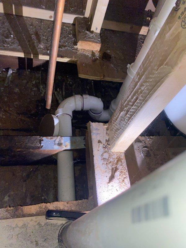 Conducted leak investigation for reported shower drainage issue affecting bedroom and wall below. Accessed utility space to inspect PVC drainage system. Found damaged elbow joint in shower drain line with visible deterioration of surrounding wooden structural supports. Identified this as the source of water intrusion causing damage to the bedroom ceiling and wall.