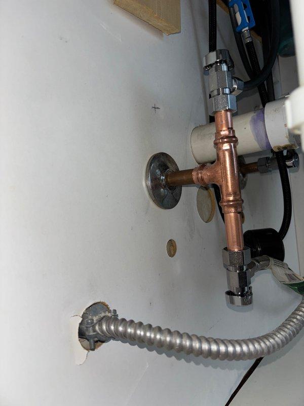 Completed wax ring replacement on basement toilet and inspected internal tank components. Examined kitchen faucet plumbing, noting P-trap configuration with PVC pipes and functional garbage disposal unit. Inspected copper pipe assembly with T-junction and verified proper connection of flexible metal conduit through wall.