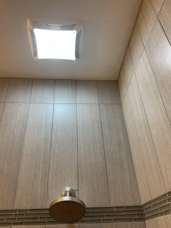 Conducted site assessment for converting standard wall-mounted shower head to rain shower system. Evaluated existing plumbing configuration, including ceiling access for overhead installation. Current setup includes wall-mounted shower head with single-handle mixer valve in beige tile surround. Recommended ceiling-mounted rain shower head with extension arm, requiring installation of additional water supply line.