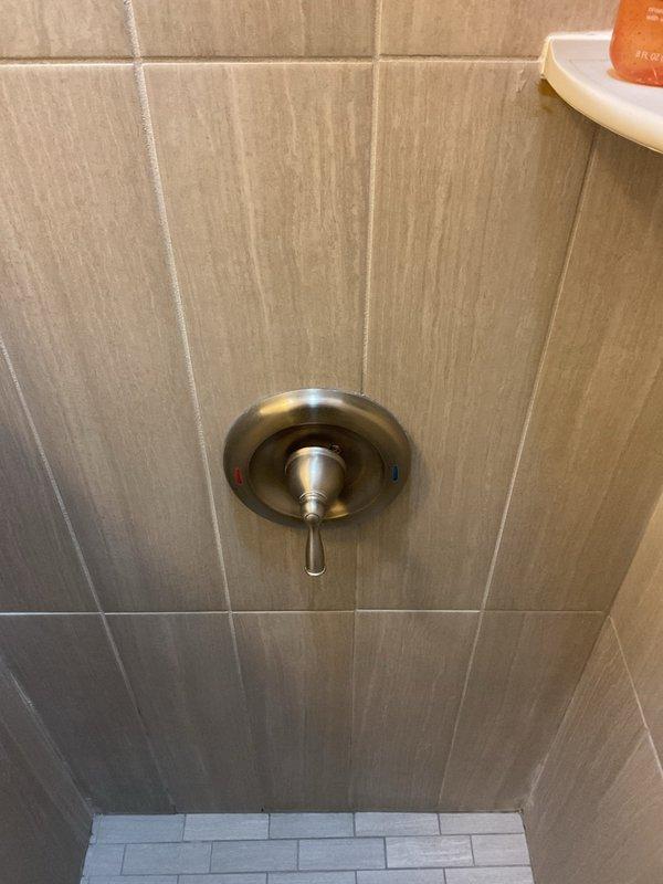 Conducted site assessment for converting standard wall-mounted shower head to rain shower system. Evaluated existing plumbing configuration, including ceiling access for overhead installation. Current setup includes wall-mounted shower head with single-handle mixer valve in beige tile surround. Recommended ceiling-mounted rain shower head with extension arm, requiring installation of additional water supply line.