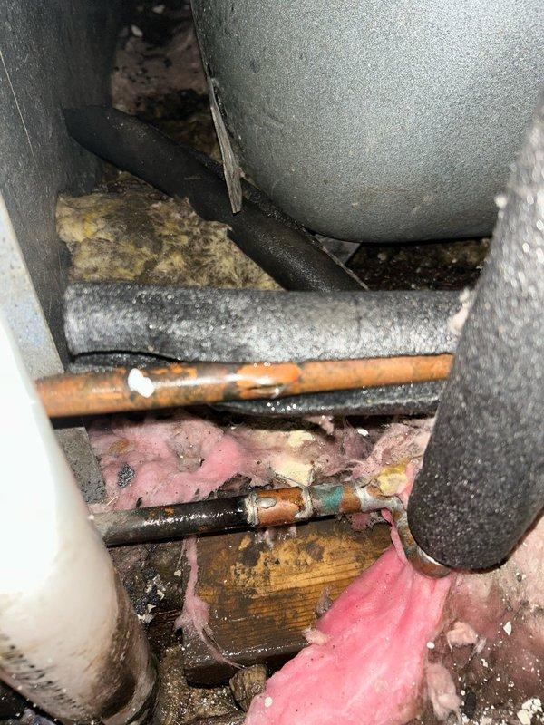 Responded to emergency service call for leak investigation. Located corroded copper pipe in utility area showing significant mineral buildup and deterioration. Discovered failed PVC drain pipe with substantial reddish-brown water pooling at base, indicating active leak. Replaced damaged pipe sections, installed new fittings, and verified system integrity with pressure test. Area cleaned and leak resolved.