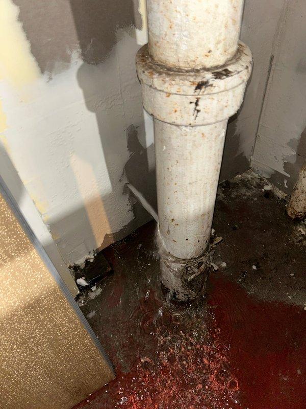 Responded to emergency service call for leak investigation. Located corroded copper pipe in utility area showing significant mineral buildup and deterioration. Discovered failed PVC drain pipe with substantial reddish-brown water pooling at base, indicating active leak. Replaced damaged pipe sections, installed new fittings, and verified system integrity with pressure test. Area cleaned and leak resolved.