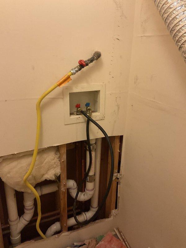 Completed assessment of exposed wall plumbing system, inspecting PVC drainage pipes, water supply connections with hot/cold valves, and associated gas line. Documented current installation configuration including U-shaped drain assembly and utility box placement for commercial drain and sewer estimate.