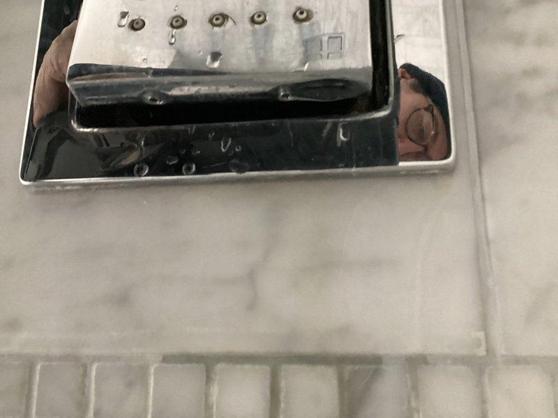 Responded to service call for toilet fixture maintenance. Replaced worn flush valve actuator mechanism and serviced electronic sensor control panel on wall-mounted urinal/toilet. Cleaned water residue from sensor panel and verified proper flush operation after installation.