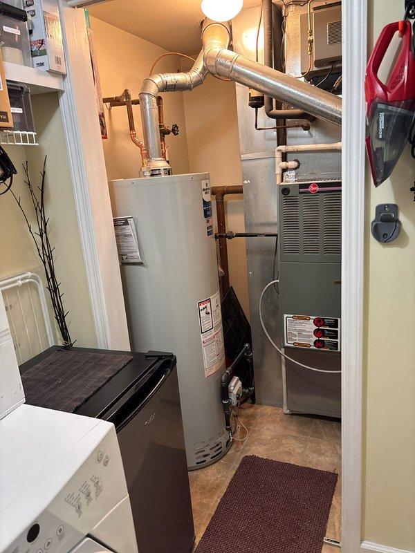 Installed new 50-gallon atmospheric water heater in residential utility room. Connected copper inlet/outlet water lines with appropriate valves and properly vented unit with galvanized metal vent pipes to existing ceiling connection. System tested and functioning correctly.