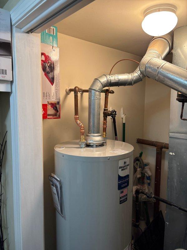 Installed new 50-gallon atmospheric water heater in residential utility room. Connected copper inlet/outlet water lines with appropriate valves and properly vented unit with galvanized metal vent pipes to existing ceiling connection. System tested and functioning correctly.
