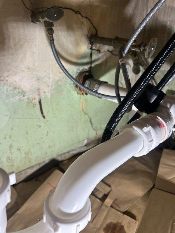 Completed plumbing repair job under sink, replacing damaged P-trap assembly and drain pipe connections. Addressed visible water damage and moisture issues, installing new PVC drainage components with proper seals at all connection points. All supply lines were secured and tested for proper drainage functionality.