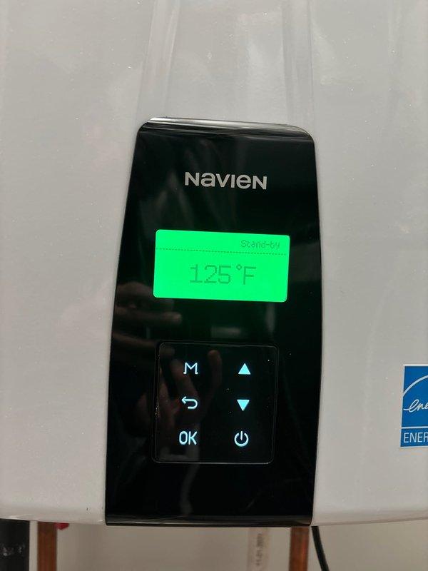 Installed and configured new Navien tankless water heater system for customer Pamela (job sold by Joey). Unit was properly mounted on wall with all necessary copper supply lines and PVC venting connected according to manufacturer specifications. System was successfully tested with control panel showing proper standby status at 125°F temperature setting and Energy Star compliance verified.