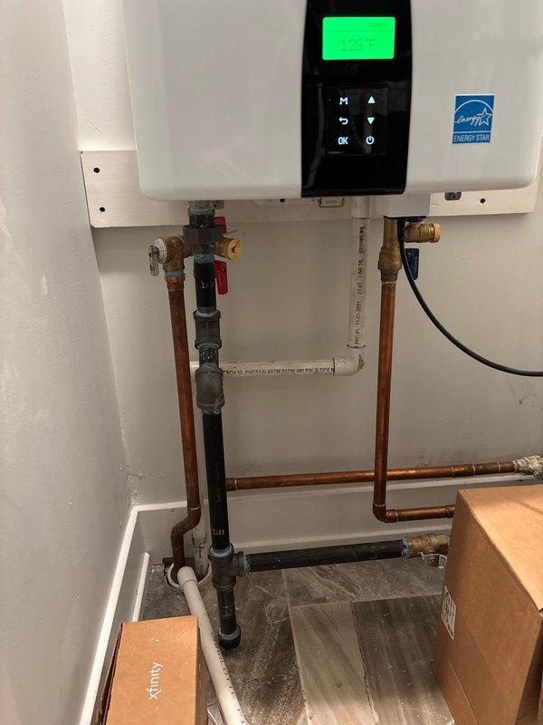 Installed and configured new Navien tankless water heater system for customer Pamela (job sold by Joey). Unit was properly mounted on wall with all necessary copper supply lines and PVC venting connected according to manufacturer specifications. System was successfully tested with control panel showing proper standby status at 125°F temperature setting and Energy Star compliance verified.