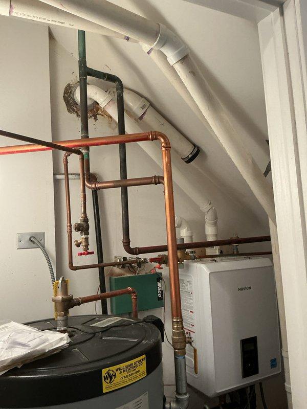 Responded to warranty call for recently installed water heater displaying error code 271 and producing only warm water. Diagnosed issue with Navien unit showing visible vapor/smoke emission from wall-mounted vent. Inspected copper and PVC piping connections in basement utility area, focusing on potential issues at joints where different materials meet.