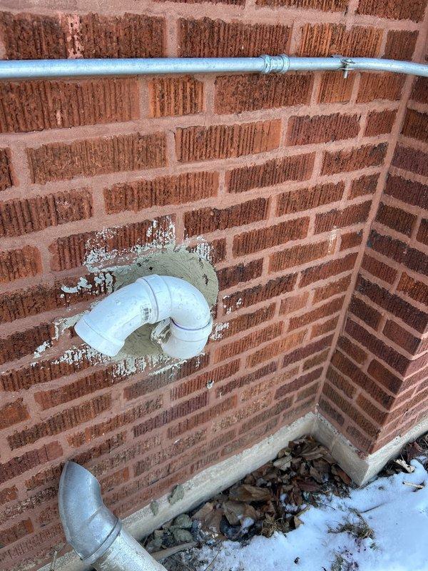 Successfully installed new Energy Star rated tankless water heater on brick wall in utility area, connecting all necessary copper and PVC piping. Completed exterior wall penetration with PVC vent pipe, properly sealed around brick opening for code compliance and optimal system ventilation.