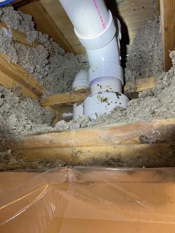 Responded to a water leak complaint where upstairs bathroom sink usage was causing water intrusion in the lower unit's bedroom closet. Inspected the plumbing system between units and identified water infiltration pathways. Examined PVC drainage pipes and connections within the joist space, noting disturbed insulation around the plumbing. Leak source was documented with photographic evidence showing the affected drainage system and surrounding structural elements.