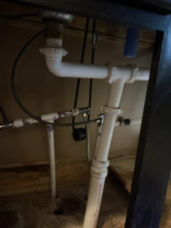 Inspected customer's under-sink plumbing system in response to reported leak. Identified a faulty elbow joint in the PVC drainage assembly near the P-trap configuration. Customer was informed that repair is covered under existing warranty terms.