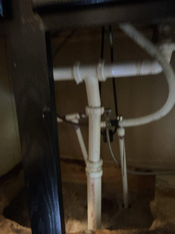 Inspected customer's under-sink plumbing system in response to reported leak. Identified a faulty elbow joint in the PVC drainage assembly near the P-trap configuration. Customer was informed that repair is covered under existing warranty terms.