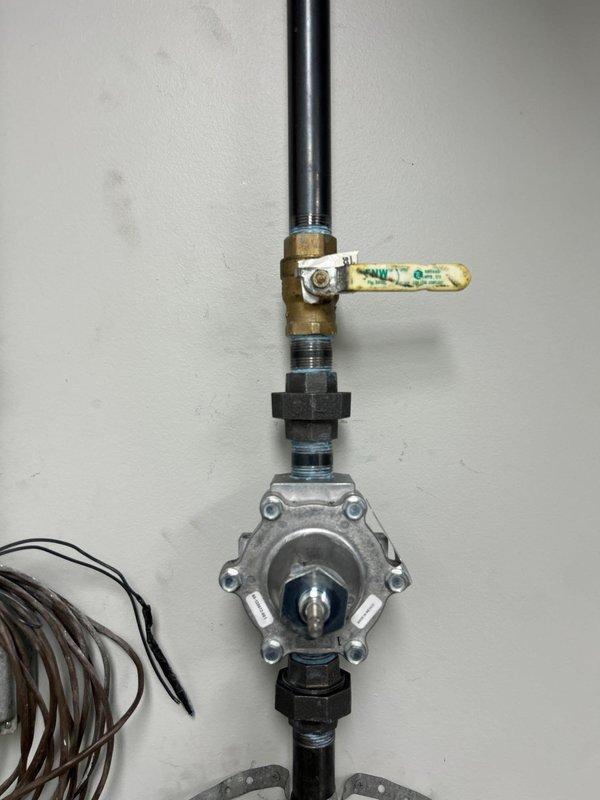 Completed sold repair job involving installation of a pressure regulator/flow control valve assembly with ball valve in ceiling service area. Accessed system through suspended ceiling, installed new brass valve with control handle and hexagonal coupling connected to the pressure regulator. System was tested and confirmed operational after installation.