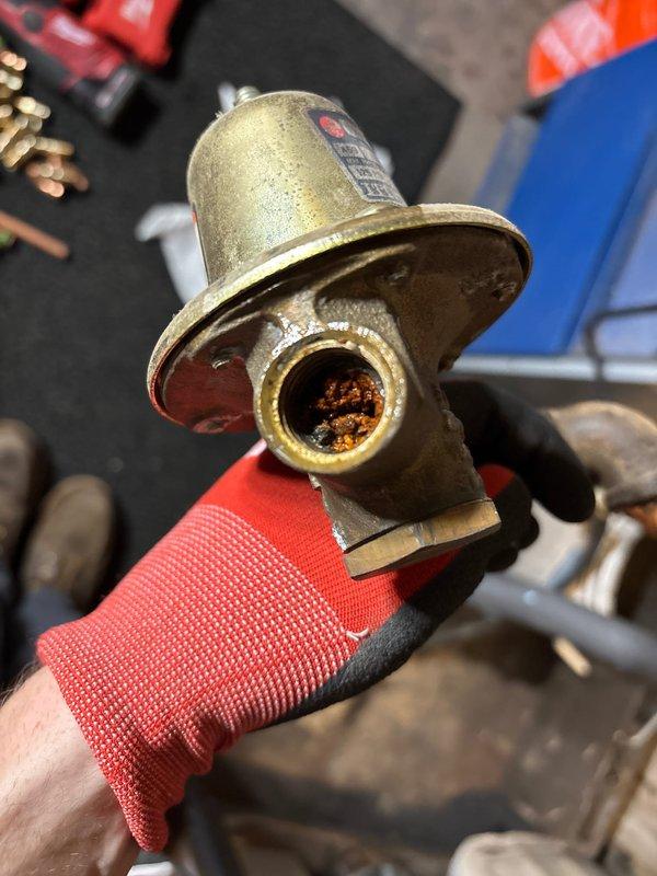 Replaced corroded brass pressure regulator valve that showed significant internal buildup and mineral deposits. Removed existing fixture from water supply line and installed new component to restore proper water pressure regulation and prevent potential leakage issues.