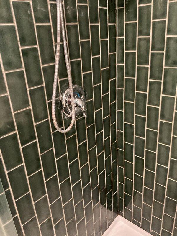 Returned to property to complete a previously sold repair job. Accessed the shower plumbing through a wall panel to service the shower fixture and associated copper supply lines. Completed necessary repairs to the shower system in the green-tiled bathroom enclosure.