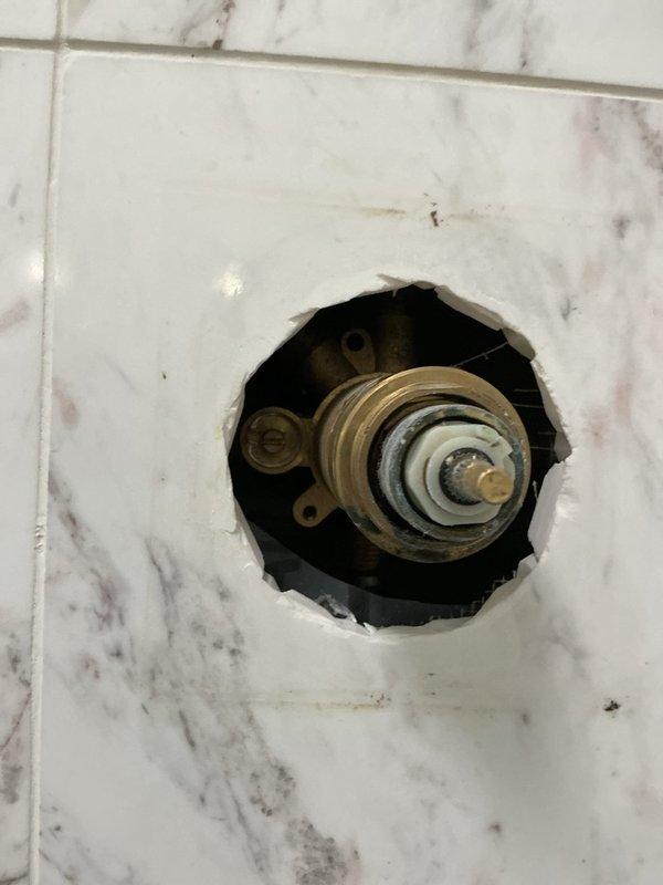 Responded to a building shut down service call to repair a shower valve assembly. Upon inspection, found the existing brass valve showing signs of mineral buildup and discoloration. Successfully removed the damaged components and installed a new valve assembly in the marble-tiled wall, ensuring proper function before completing the service.