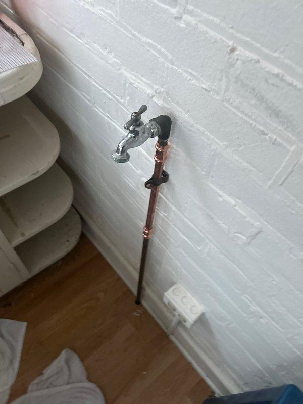 Responded to emergency call for burst copper pipe in screened porch area that extends to basement. Removed damaged section of pipe which showed signs of oxidation and wear. Installed new copper supply line with proper wall mounting bracket and connected to existing water faucet fixture on brick wall, restoring water service to the area.
