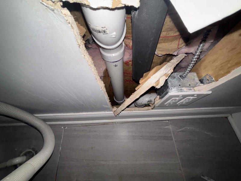 Responded to service call for water backing up from laundry pipe. Inspection revealed damaged drywall/ceiling around the drainage system with a white PVC pipe showing signs of previous rodding. Found water damage around the washing machine connection box with compromised drain line. Cleared blockage and verified proper drainage function.
