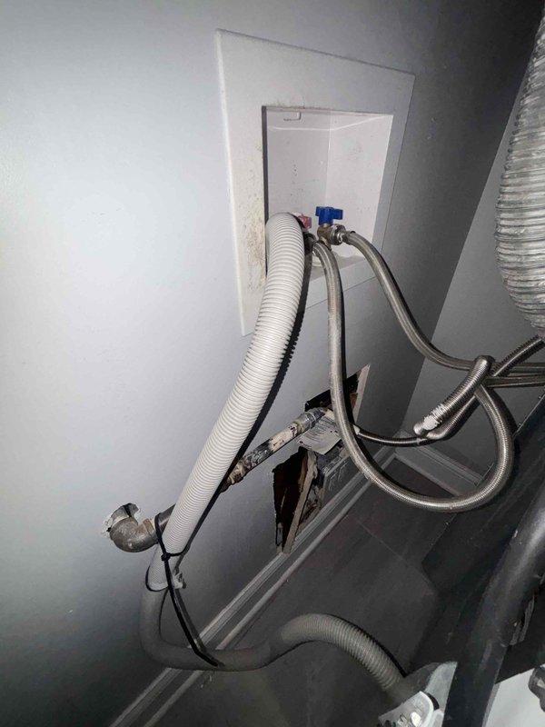 Responded to service call for water backing up from laundry pipe. Inspection revealed damaged drywall/ceiling around the drainage system with a white PVC pipe showing signs of previous rodding. Found water damage around the washing machine connection box with compromised drain line. Cleared blockage and verified proper drainage function.