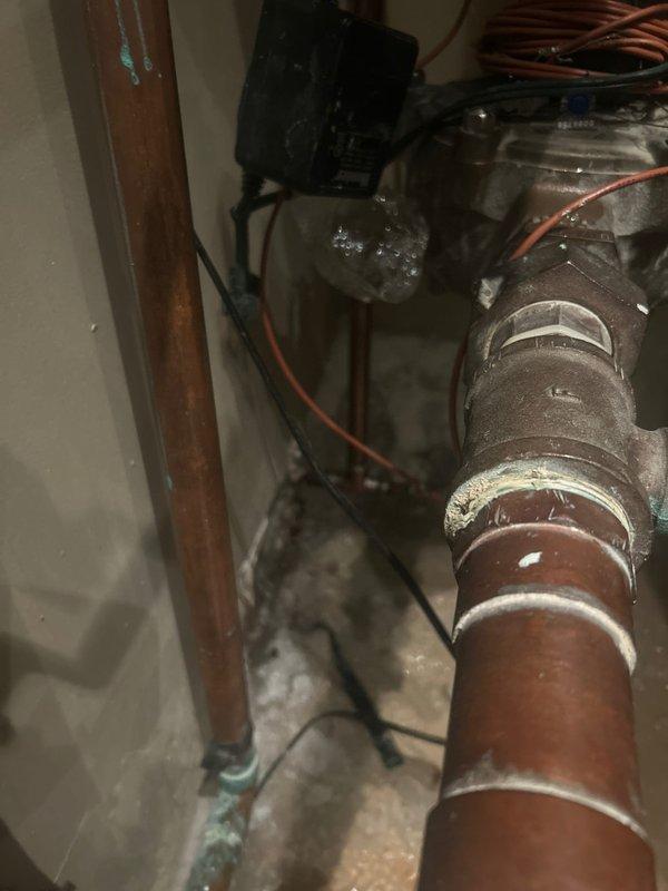 Responded to emergency service call for frozen pipes causing water leak. Inspected copper pipe system showing significant corrosion and oxidation. Located and replaced damaged valve assembly, addressing pipe sections exhibiting green patina formation. Restored proper water flow and verified system integrity after repair.