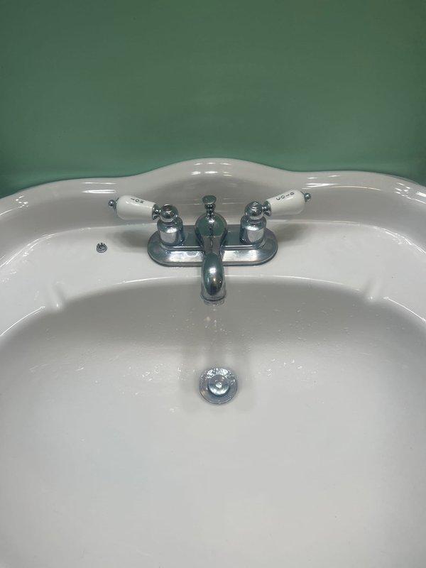 Diagnosed bathroom sink faucet leak issue that persisted despite previous cartridge replacement. Inspected chrome two-handle faucet mounted on white porcelain sink and determined complete faucet replacement was necessary due to internal valve body damage. Installed new faucet assembly, verified proper operation with no leaks.