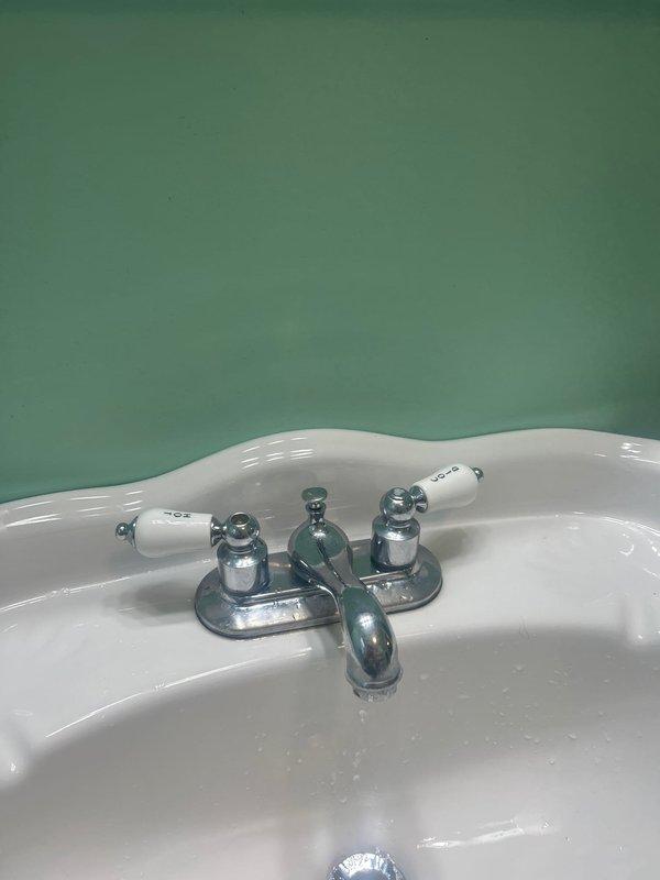 Diagnosed bathroom sink faucet leak issue that persisted despite previous cartridge replacement. Inspected chrome two-handle faucet mounted on white porcelain sink and determined complete faucet replacement was necessary due to internal valve body damage. Installed new faucet assembly, verified proper operation with no leaks.